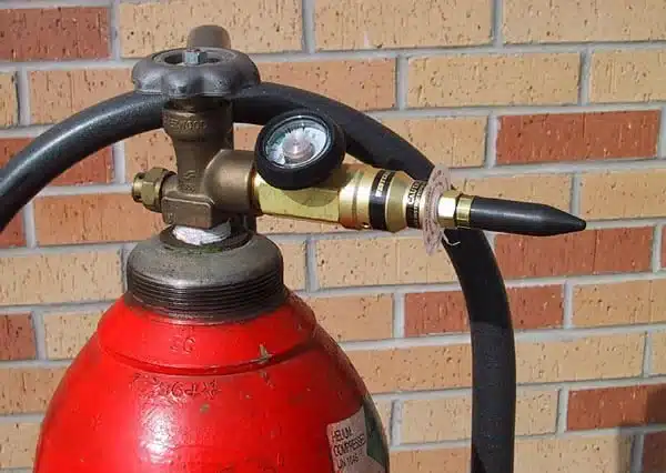 Red helium cylinder with a balloon filler regulator attached to the valve