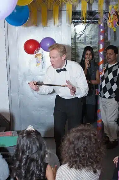 Kids magician holding a magic wand on stage at a children's party