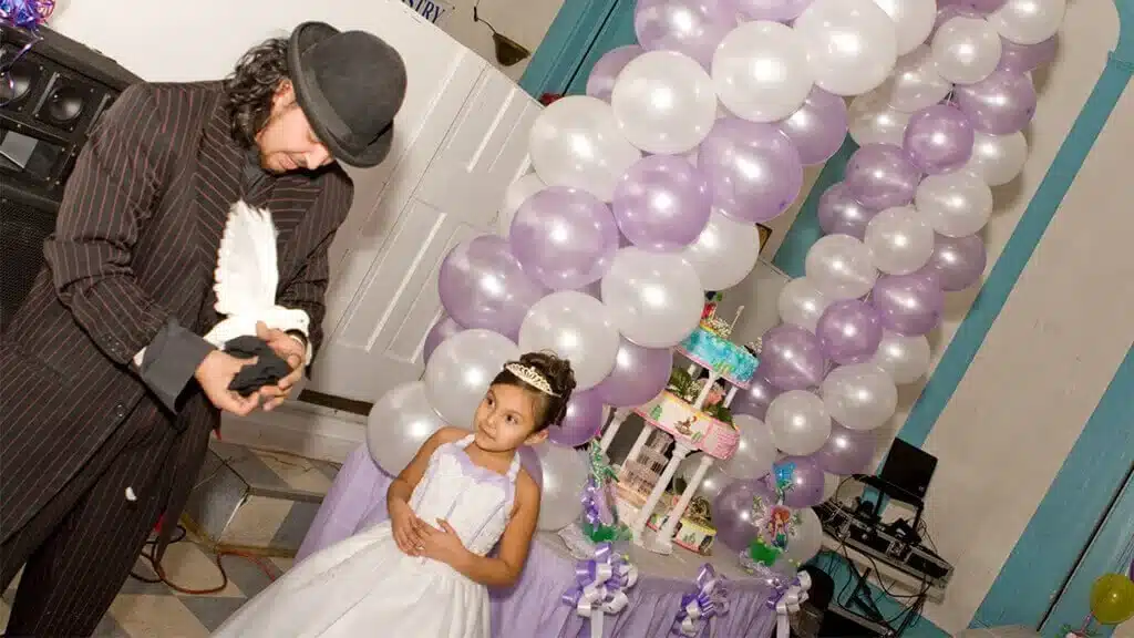 Magician performing with a dove next to the birthday girl at a party