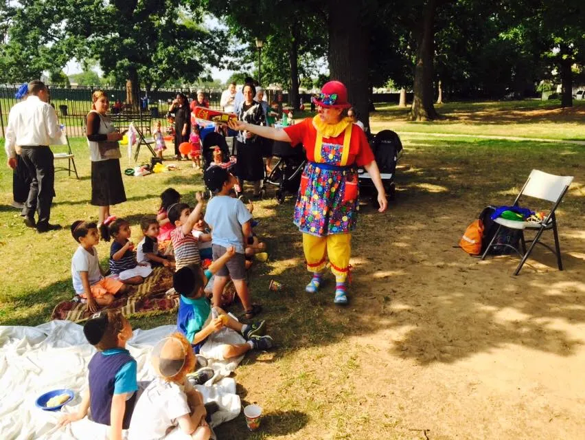 Clown performing magic tricks for kids at a birthday party