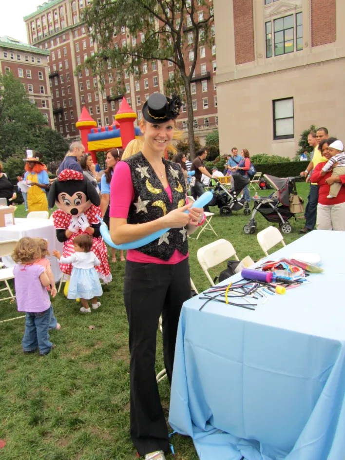Balloon artist twisting a balloon animal for kids at an outdoor event in NYC