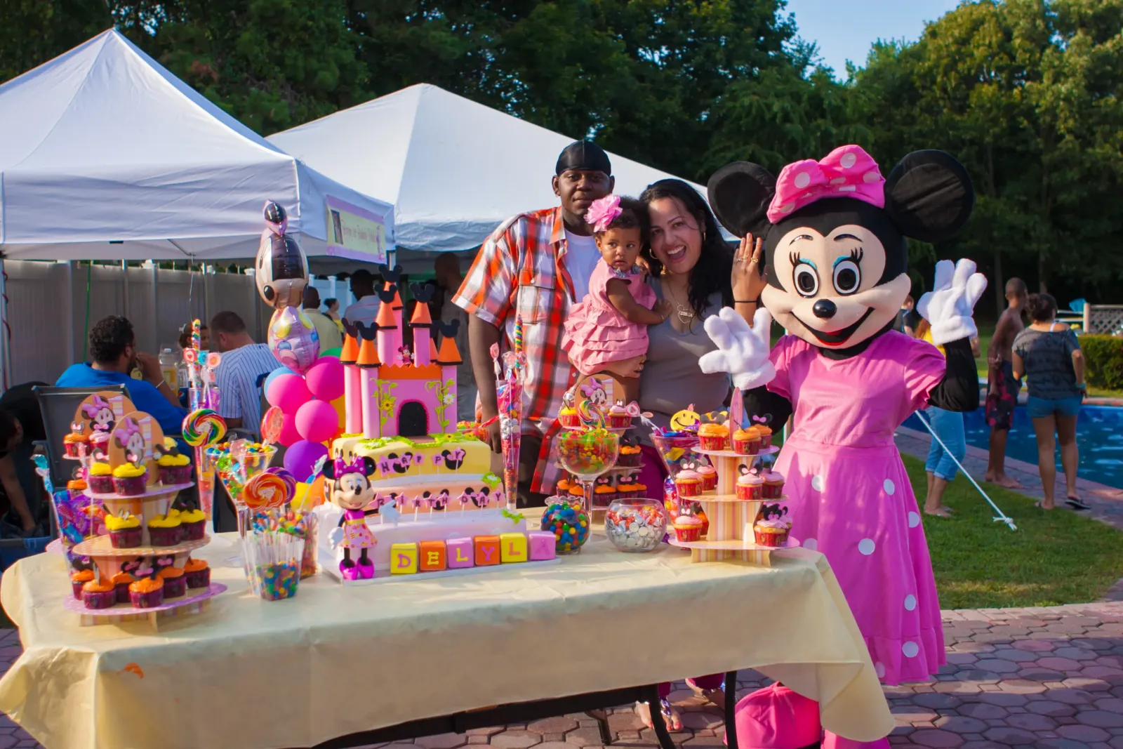 Backyard kids birthday party with white canopy tents, a candy table, a castle cake and a mouse costume character