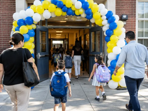 Balloon arch in yellow, blue and white framing the front doors of a New York elementary school