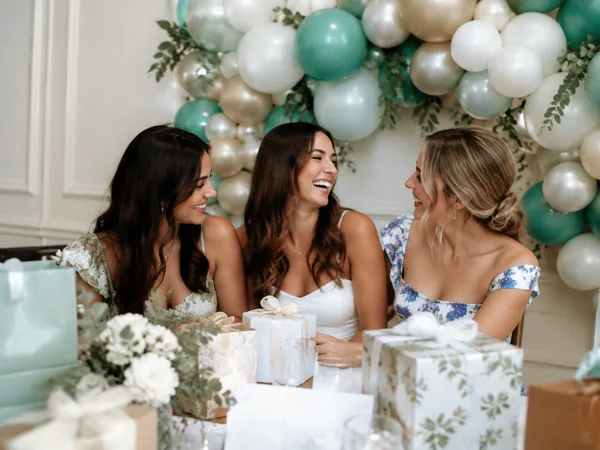 Balloon backdrop in teal, white and pearl with greenery behind a bridal shower table