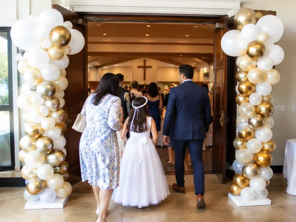 Pair of balloon columns in white, ivory and gold at the entrance of a church hall
