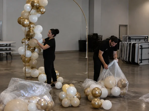 Crew taking down a balloon garland and packing balloons into bags after a party