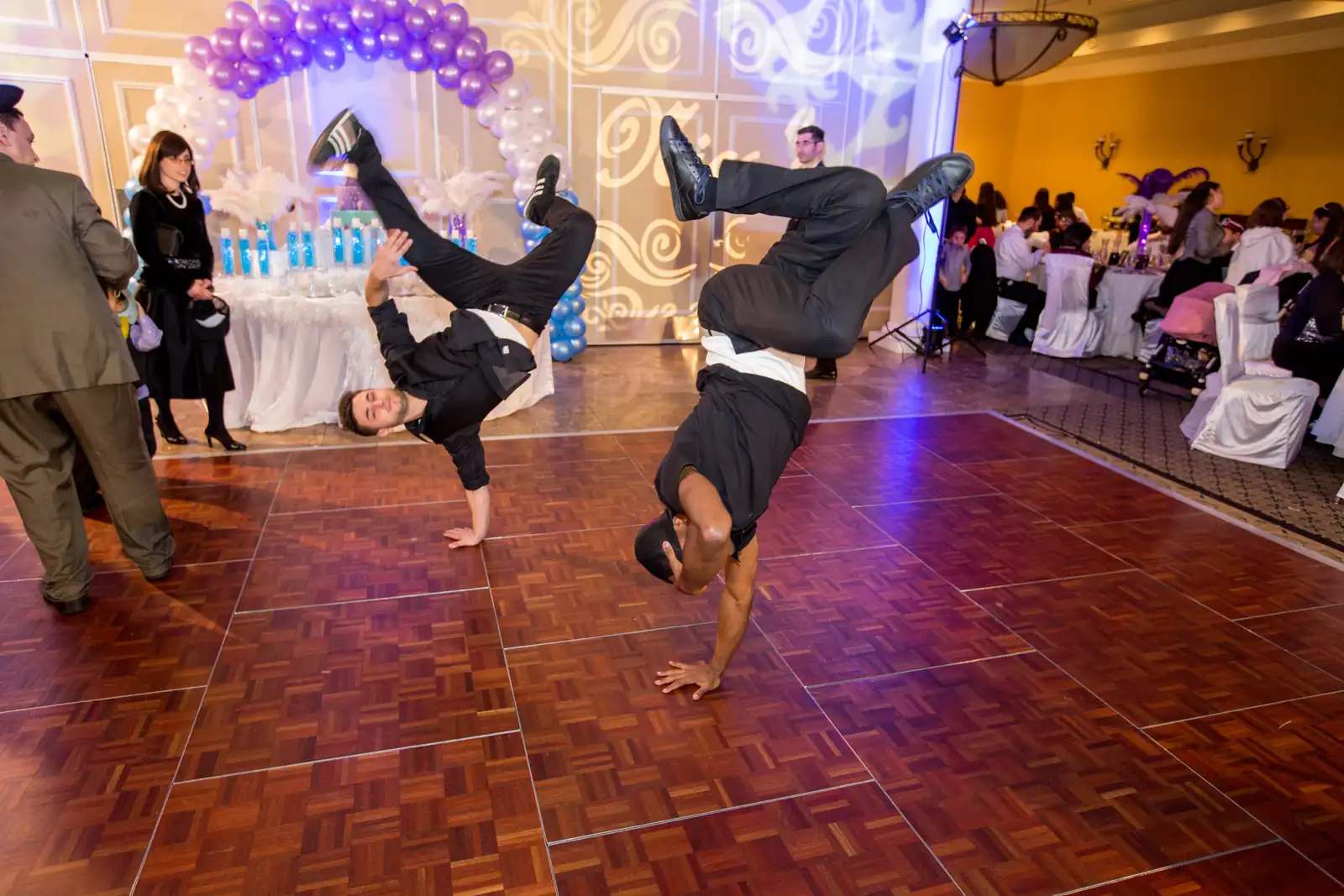 Two break dancers doing freezes and handstands on the dance floor at a bar mitzvah