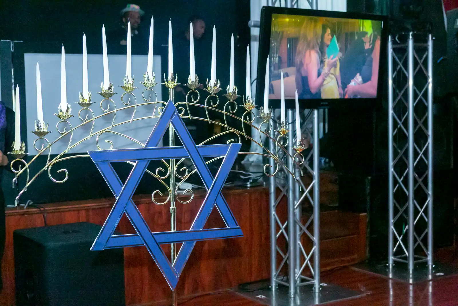 Star of David candelabra with white candles on a bar mitzvah stage with truss and TV screens