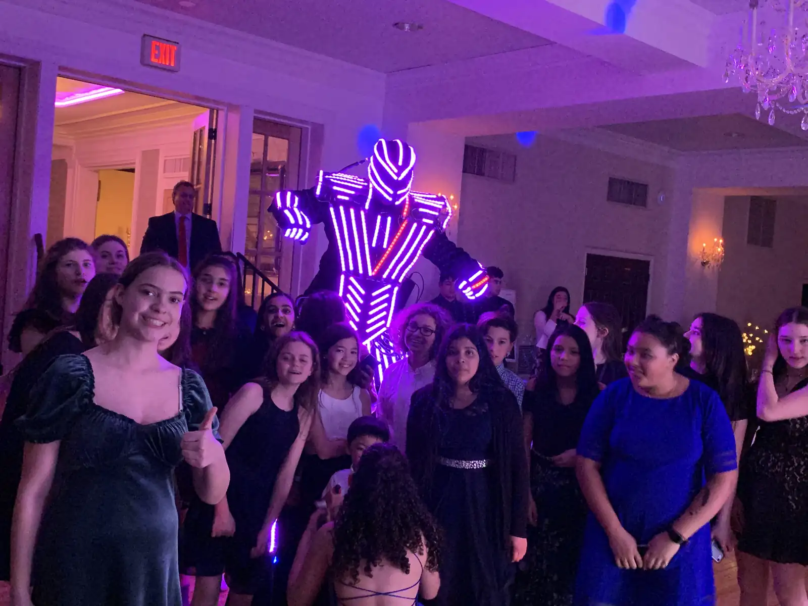 LED robot performer lit in purple posing with teens at a bat mitzvah party