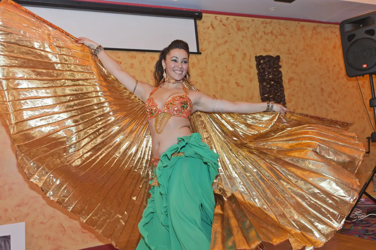 Belly dancer opening gold Isis wings at a restaurant party