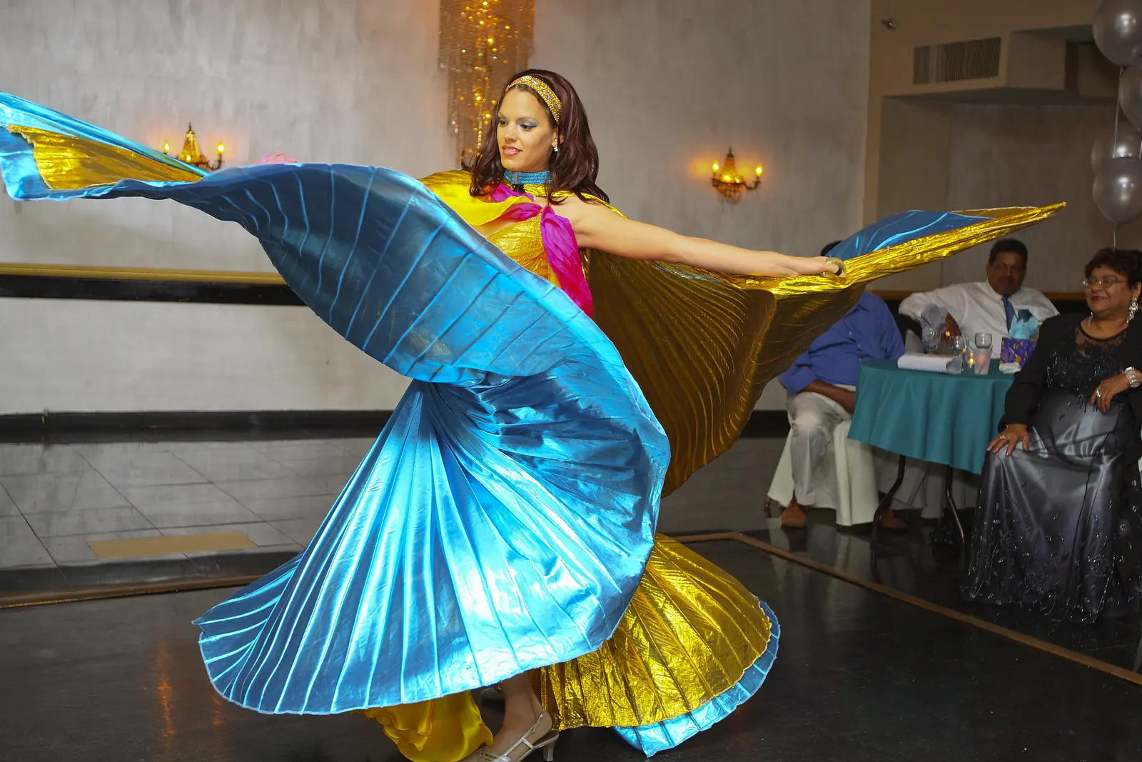 Belly dancer spinning colorful Isis wings on the dance floor at a birthday party