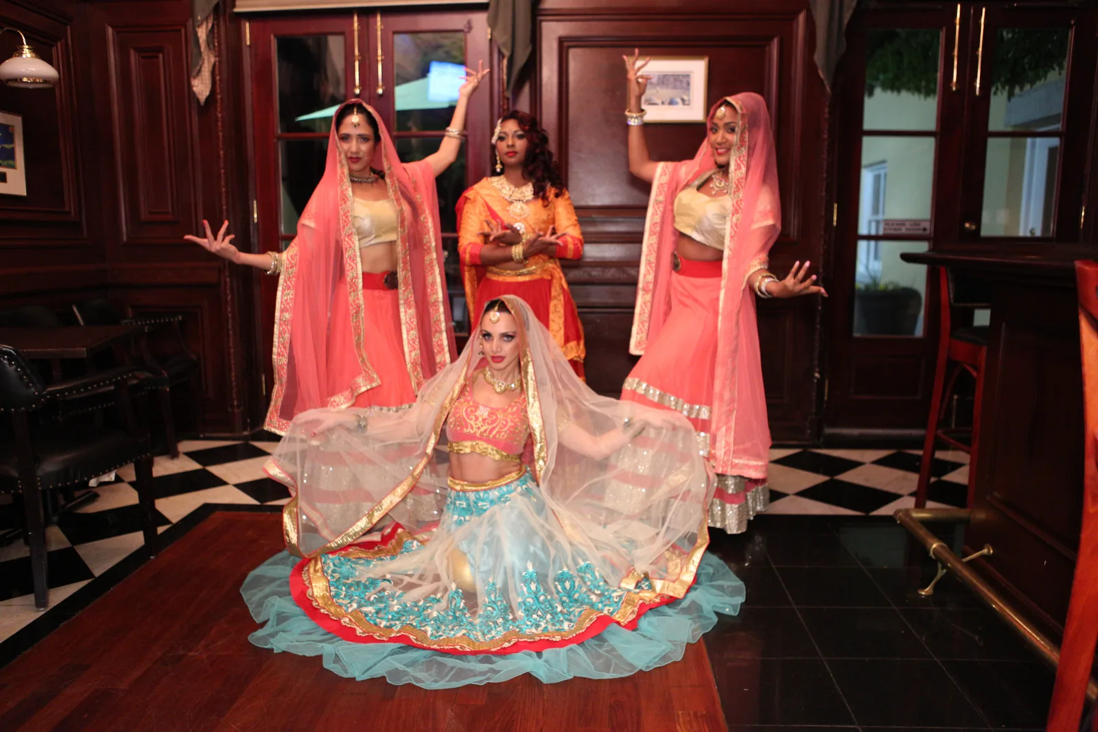 Four Bollywood dancers in traditional lehengas and veils at an event