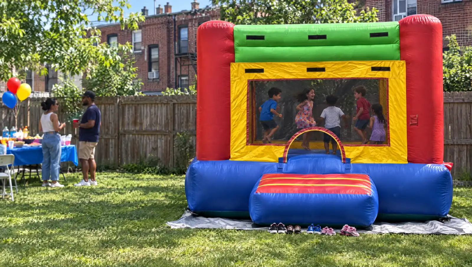 Bounce house rental at a backyard birthday party in Brooklyn, kids jumping inside and shoes lined up at the entrance