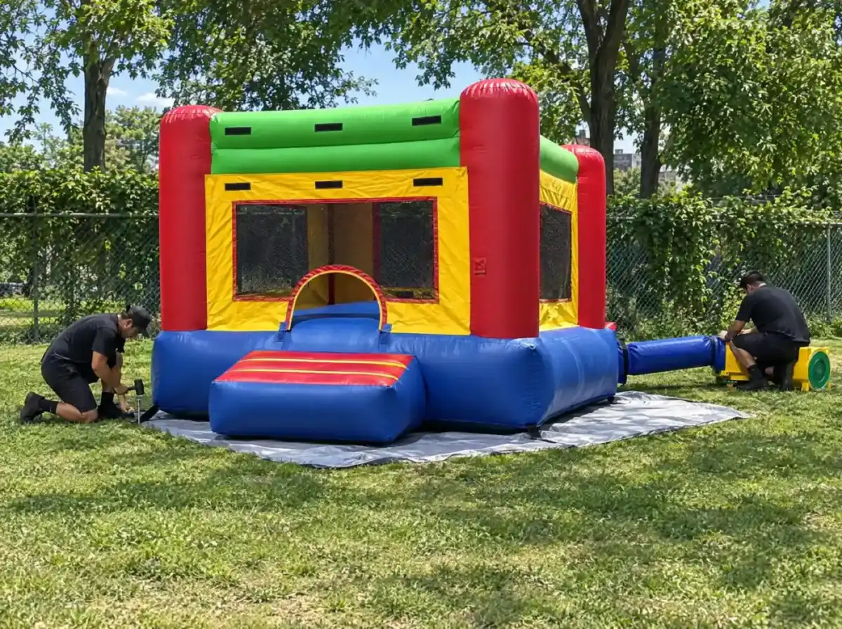 Crew staking a bounce house and connecting the blower for an inflatable rental order
