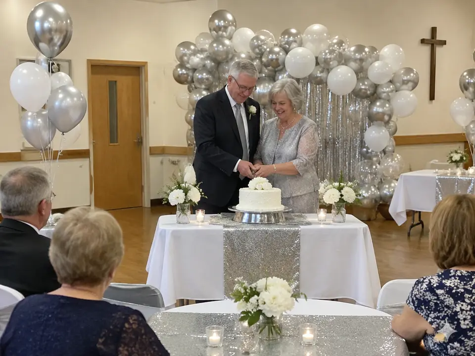 Silver and white balloon backdrop and silver table runners at a 25th anniversary party in a parish hall
