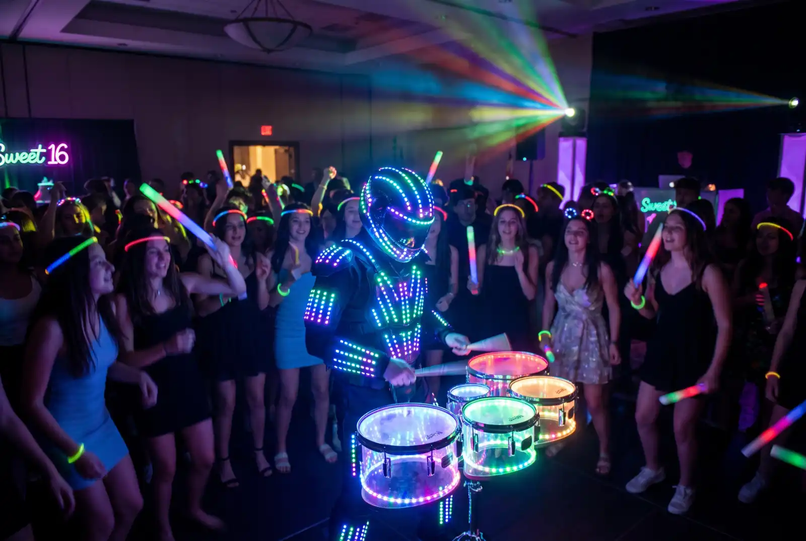 LED drummer playing lit drums in the middle of the dance floor at a Sweet 16 with teens holding glow sticks